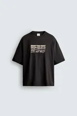 Camiseta de corte relajado color negro, con cuello redondo y manga corta. Presenta bordados a contraste en el frente con la frase 'Drop the beat' repetida en diferentes estilos tipográficos.