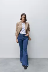 Jean flare de tiro alto, color azul, con calce ajustado en cadera y muslos, y ruedo desflecado.