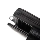 Billetera XL de textura granulada en color negro, con cierre perimetral y solapa frontal con broche decorado con una flor metálica.