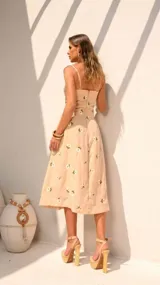 Vestido midi color beige con estampado de flores blancas, breteles finos y escote con cordones.