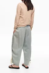 Pantalón jogger de denim celeste claro, confeccionado en mezcla de lyocell y algodón, con tiro bajo, cintura elástica y bajos fruncidos con tiras ajustables.