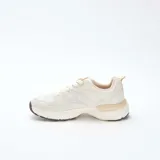 Zapatillas estilo running de color beige, confeccionadas con una combinación de paneles de cuero sintético y malla transpirable. Presentan cordones al tono, suela robusta con relieve y detalles en color marrón oscuro en la base.