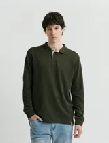 Remera de manga larga con cuello polo, confeccionada en tejido de punto canalé francés. Presenta abotonadura frontal con botones de madera y detalles a contratono en la cartera y el interior del cuello.