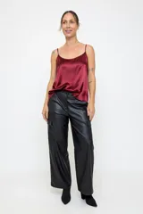 Pantalón cargo de corte recto y tiro medio, confeccionado en eco cuero negro. Presenta bolsillos laterales tipo cargo, cierre frontal con botón y bragueta, y un acabado liso con brillo sutil.