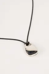 Collar con dije plateado en forma de gota y cordón negro.