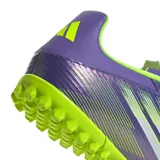 Championes de fútbol Adidas F50 Club para césped sintético, con diseño aerodinámico en tonos violeta y verde lima. Presenta cierre con cordones, suela con tapones pequeños para tracción y el logo F50 estampado en el frente.