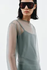 Top de tejido doble combinado semitransparente color verde, compuesto por una musculosa interior y una capa superior de manga larga con cuello redondo.
