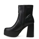Botas de caña media Miss Carol modelo Placid, confeccionadas en material sintético elastizado color negro. Presentan una plataforma alta y un taco cuadrado robusto, con un diseño minimalista y ajustado al tobillo.