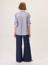 Camisa de manga larga con diseño combinado. Presenta mangas y parte superior delantera y trasera en color negro liso, mientras que el panel central de la espalda destaca por un estampado animal print de leopardo. Cuenta con cuello clásico, cierre frontal de botones y puños abotonados.