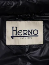 Campera larga de nylon color azul marino, con relleno de plumas, cuello alto y cierre con botones a presión.