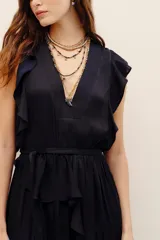 Vestido corto negro de poliéster, con escote en V pronunciado, mangas sisa con volados y lazo ajustable en la cintura.