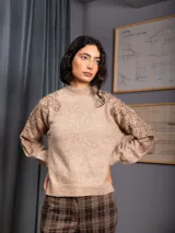 Buzo de cuello alto color gris, de manga larga, con detalle de bordado floral con lentejuelas en el hombro y parte superior de la manga.