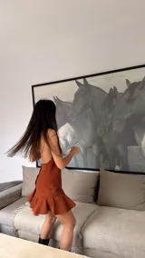 Vestido corto de cuero sintético color marrón, con diseño halter y escote profundo. Presenta un ajuste en el cuello, espalda descubierta y un volado ancho en el ruedo que aporta movimiento.