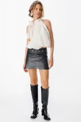 Mini falda tipo cruzada confeccionada en cuero, con detalle de cintura con tachas metálicas.