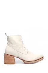 Bota corta de cuero color beige, con taco cuadrado de madera y plataforma baja. Presenta costuras decorativas laterales y tirador en la parte superior trasera.