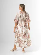 Vestido midi de estilo campesino confeccionado en organdí con estampa floral chintz de estilo romántico. Presenta escote en V cruzado, cintura completamente elastizada y falda larga con volados en niveles. Las mangas son tres cuartos con volados en los puños.