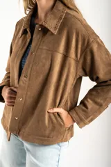 Sobrecamisa de gamuza sintética color camel, con corte oversize, cuello clásico con detalle de costura, cierre frontal con botones metálicos y mangas largas.