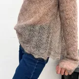 Sweater de punto calado confeccionado en 100% mohair italiano, con cuello redondo y mangas largas. Presenta una textura aireada y delicada con un diseño etéreo y sofisticado.
