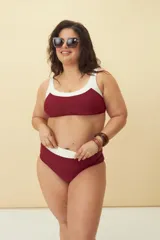 Conjunto de bikini compuesto por un top deportivo con escote redondo y una bombacha de tiro alto, ambos en color bordó con detalles en blanco en los bordes.