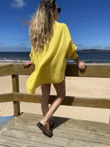 Camisa amarilla de lino, corte oversize, con cuello clásico, cierre frontal con botones y mangas largas con puños elastizados.