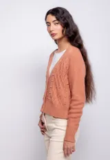Cardigan color beige con trama de punto trenzado, cuello en V y cierre frontal con botones.