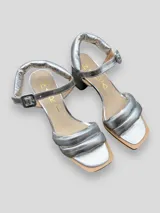 Sandalias plateadas de cuero con tiras acolchadas, taco cuadrado bajo y pulsera con hebilla.