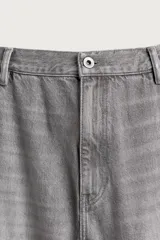 Jeans relaxed fit de tiro medio y pernera recta confeccionados en denim de algodón rígido, con diseño de carpintero que incluye bolsillos superpuestos y roturas localizadas en el frente.