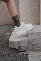 Zapatilla de plataforma alta, color blanco, con diseño monocolor, cierre mediante cordones y punta redonda.