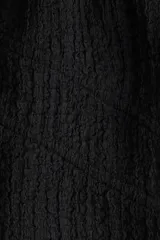 Top corto negro con textura arrugada, escote en V pronunciado y cordones de ajuste cruzados en la parte delantera. Presenta mangas cortas abullonadas con elástico en el borde.