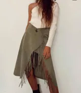 Pollera cruzada color verde militar, de largo midi, con detalle de flecos largos en el borde. Presenta un botón oscuro en la cintura para el ajuste.