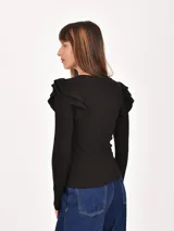 Remera negra de manga larga, con cuello redondo y volados en los hombros.