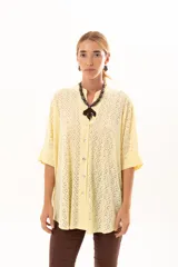 Camisa de corte oversize y mangas murciélago, confeccionada en tela con perforaciones tipo broderie. Presenta cuello mao, cierre frontal con botones y un diseño holgado y fluido.