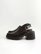 Zapato tipo slingback color negro, con plataforma y taco cuadrado. Presenta una puntera cuadrada y cierre con hebilla metálica en la tira trasera.