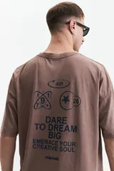 Remera de algodón color marrón con efecto gastado (acid wash), corte boxy holgado y hombros caídos. Presenta un estampado gráfico en la espalda con motivos circulares, estrellas, números y el texto "DARE TO DREAM BIG EMBRACE YOUR CREATIVE SOUL" y el logo "mistral".