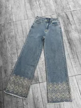 Pantalón de jean celeste de corte recto con bordado floral en el ruedo.