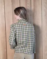 Camisa de algodón con estampado de rayas verticales finas, cuello alto con volados, cierre frontal con botones dobles y mangas largas con puños elásticos terminados en volados.