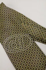 Corbata de seda color amarillo pálido con estampado geométrico en azul marino y marrón. Presenta un logo bordado en blanco.