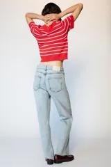 Jeans de tiro alto con diseño de cintura cruzada, cinco bolsillos y pernera recta con bajo sin costura. Cierre frontal con cremallera y botones.