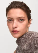 Chaleco de punto jaspeado en tonos marrones, con cuello envolvente y diseño sin mangas. Presenta una silueta recta y tejido de algodón de textura gruesa.