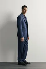 Pantalón de traje de corte regular fit en color azul marino, confeccionado en una mezcla de lino y lana. Cuenta con bolsillos delanteros, bolsillos traseros de doble vivo con botón y raya marcada en el centro de las piernas.