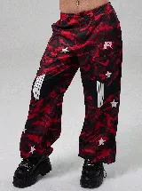 Pantalón de tiro bajo con estampado de camuflaje en tonos rojos y negros. Presenta diseño holgado, detalles de estrellas blancas aplicadas, paneles laterales con franjas verticales y bolsillos cargo.