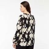 Blusa de manga larga con cuello en V, confeccionada en tejido ligero con estampado floral en blanco y negro.