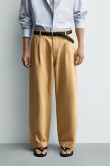Pantalón chino straight fit de corte recto y holgado, color tostado, con pliegues frontales en la cintura, bolsillos laterales y cierre con cremallera y botón.