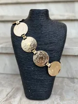 Cinto dorado de metal con eslabones y monedas circulares texturizadas.