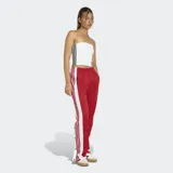 Pantalon deportivo Adidas modelo Adibreak, color rojo con franjas laterales blancas y botones a presión. Presenta cintura elástica y corte holgado.