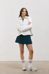 Buzo de algodón con diseño bicolor en blanco y verde inglés, cuello tipo chomba con botones frontales, mangas largas con puños y corte holgado a la cintura.