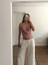 Top con cuello halter y espalda descubierta, confeccionado en tejido de lentejuelas color rosado.