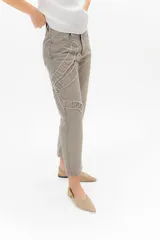 Jean gris lavado, estilo mom fit, con aplique fruncido en forma de espiral en la pierna izquierda, tiro alto, bolsillos delanteros y traseros funcionales, y cierre frontal con botón y cremallera.