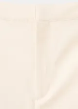 Pantalón de tiro alto color crudo, con diseño largo y corte recto. Cuenta con trabillas, bolsillos laterales y cierre frontal oculto con cremallera, botón y ganchos.
