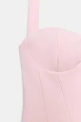 Top halter de color rosado con escote corazón y detalle de frunces en el delantero. Cuenta con cierre lateral mediante cremallera oculta.
